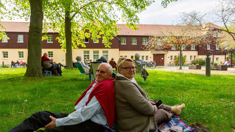 Angela und Hans Grobert sitzen Rücken an Rücken auf der Wiese vor den Parksälen in Dippoldiswalde. Sie genießen nach langer Corona-Durststrecke das Konzert sichtlich.