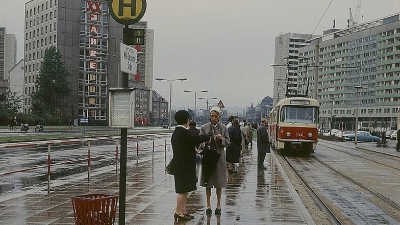 Rote Straßenbahn, altmodisches Haltestellenschild, wenig Verkehr – die Leningrader zu Beginn.