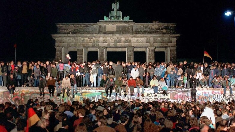Am Brandenburger Tor wird die ganze Nacht gefeiert. Berliner aus Ost und West sind auf die drei Meter breite Panzermauer geklettert.