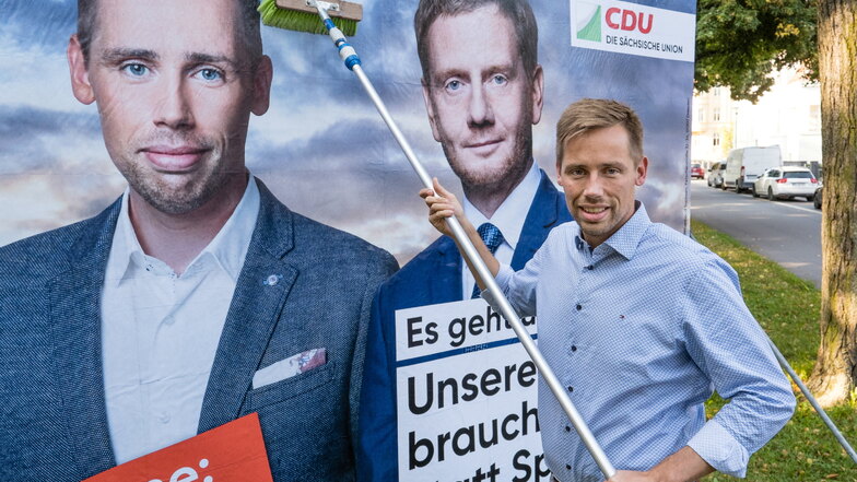 CDU-Kandidat Florian Oest klebt ein neues Wahlwerbeplakat auf der Goethestraße in Görlitz.