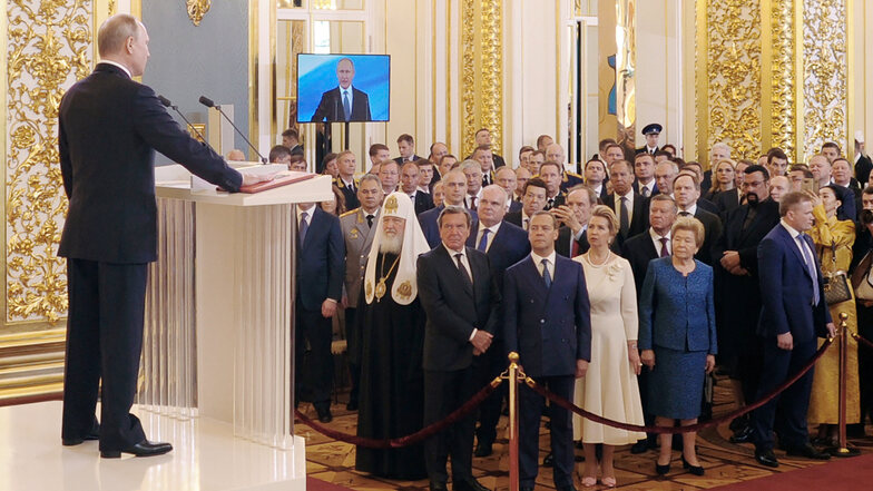 Wladimir Putin (l), Präsident von Russland, spricht bei seiner Amtseinführung als neuer Präsident iim Mai im Kreml, während er seine Hand auf die Verfassung legt. 