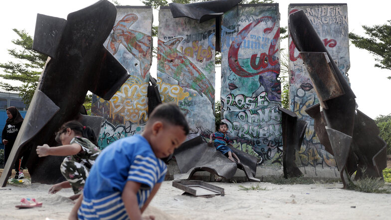 Indonesien, Jakarta: Kinder spielen in der Nähe von Mauerstücken, die als Teil einer Installationskunst des indonesischen Künstlers Teguh Ostenrik im Kalijodo Park aufgestellt wurden. 