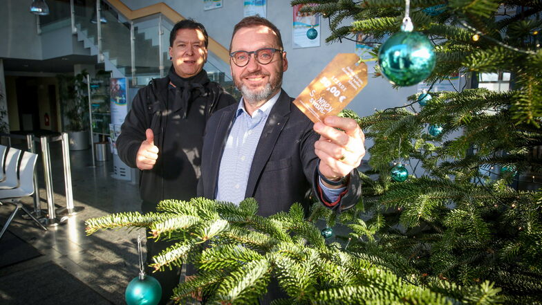Ewag-Chef Torsten Pfuhl (r.)  und Jörg Demski vom Sonnenstrahl-Verein freuen sich, dass die Spendenaktion am Weihnachtsbaum im Foyer des Kamenzer Energieunternehmens schon gut angenommen wird.
