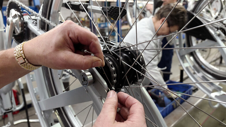 Ein Mitarbeiter des Fahrradherstellers Sachsenring Bike Manufaktur GmbH montiert einen Bowdenzug an die Nabe eines Fahrrades an einer Taktstraße in dem Unternehmen.