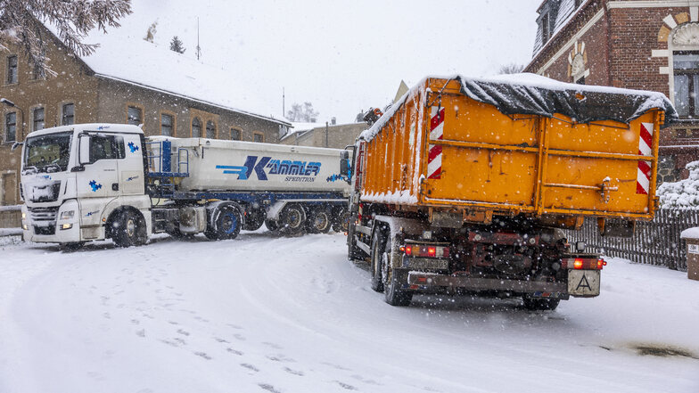 Lastwagen kämpfen sich auf den schneebedeckten Straßen durch das Erzgebirge. Einige hängen an steilen Strecken fest.