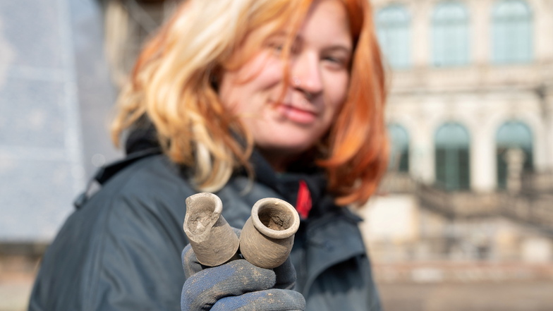 Grabungsarbeiterin Fara Freitag zeigt aus dem Untergrund geborgene Keramikgefäße, in denen früher Salben aufbewahrt wurden.