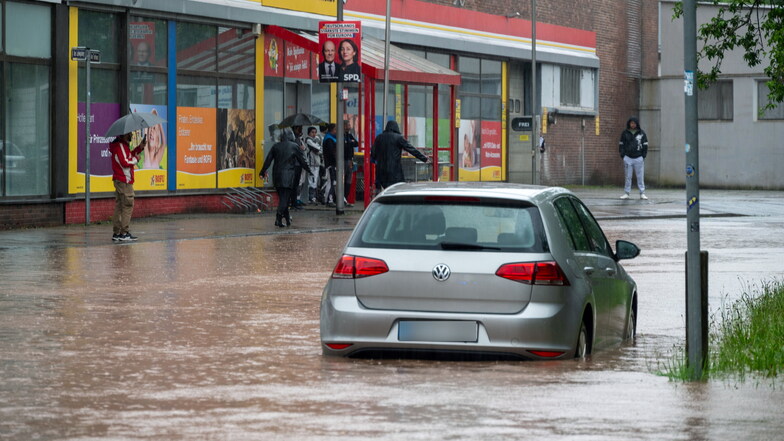 Passanten stapfen und fahren durch das Hochwasser in Saarbrücken.