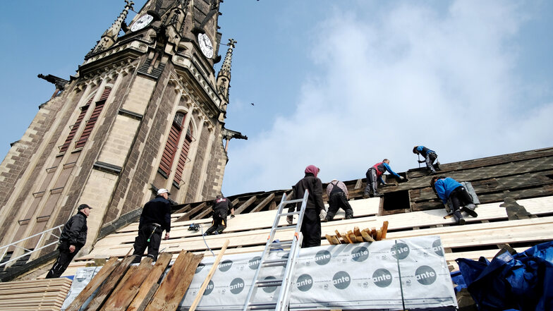 Männer der Dresdner Dachdeckerfirma Wagner bauen eine neue Schalung auf die Südseite des Kirchendaches. Dort werden später die Schindeln aus Naturschiefer aufgenagelt.