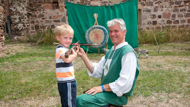 Der fünfjährige Quirin aus Seifersdorf übt sich im Bogenschießen und wird dabei von Frank Enderlein (rechts) angeleitet.