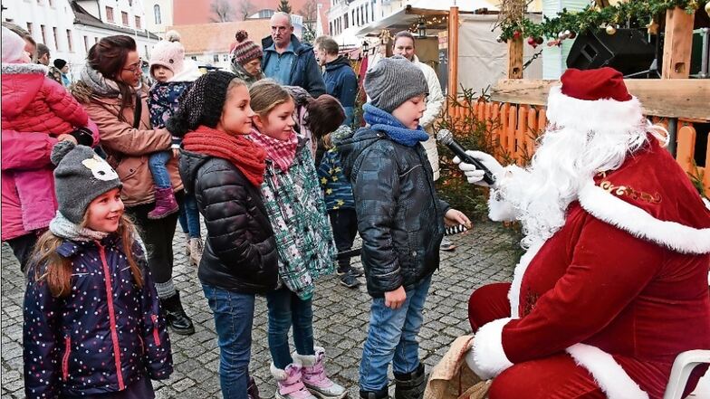 Vor der Bühne auf dem Markt in Rothenburg empfängt der Weihnachtsmann die jüngeren Besucher und belohnt sie mit einem Geschenk für ihr Lied oder Gedicht.