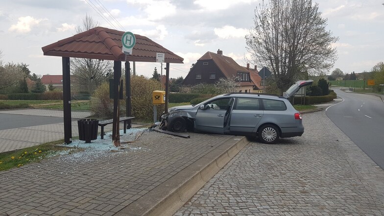 Ein Bild von der Unfallstelle: Die Front des VW ist komplett hinüber. Im Buswartehäuschen sind die Scheiben zertrümmert.