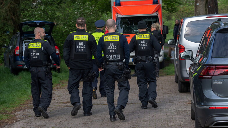Polizeibeamte gehen auf einem Weg zu einer Parkanlage in Berlin-Zehlendorf. Dort wurde am frühen Morgen des Sonnabends ein schwer verletzter Mann gefunden.
