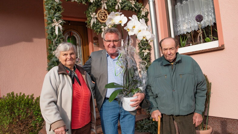 Fritz und Elfriede Wilhelm feiern ihren 65. Hochzeitstag, die eiserne Hochzeit, in Kraußnitz bei Ortrand. Schönfelds Bürgermeister Hans-Joachim Weigel (M.) gratuliert mit einer großen Orchidee.