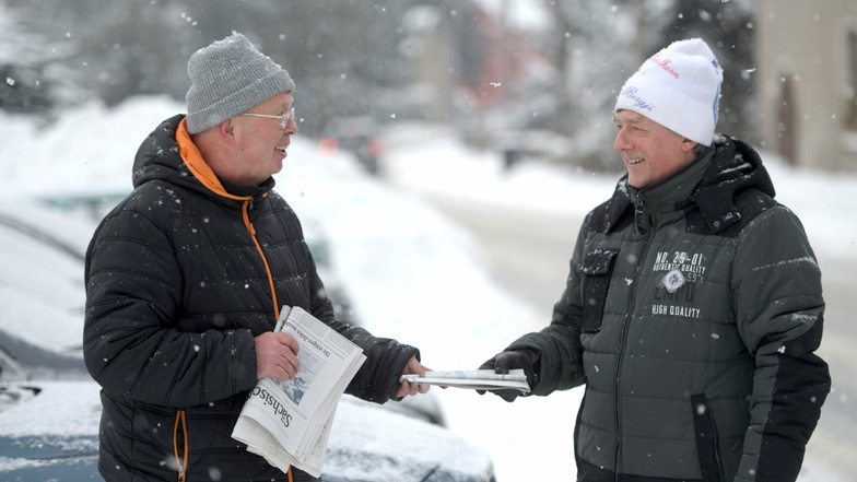 Mathias Schwenke (links) bringt in Oppach und Beiersdorf die Zeitung - auch jetzt im Schneesturm. Matthias Wünsche wartet schon und nimmt sie entgegen.