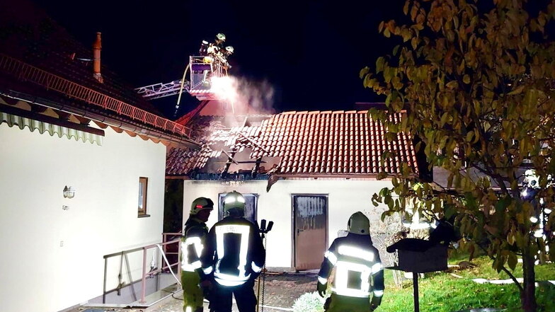 Feuerwehrleute löschen in der Nacht zu Mittwoch den Brand in einer Doppelgarage in Hohnstein.