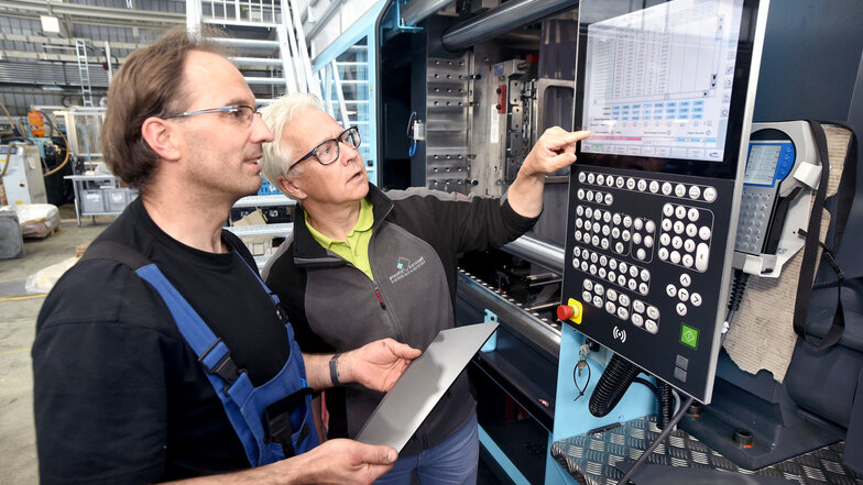 Bernd Nebel, Geschäftsführer von Plastic Concept, und Mitarbeiter Frank Kriegel an einer Spritzgussmaschine.