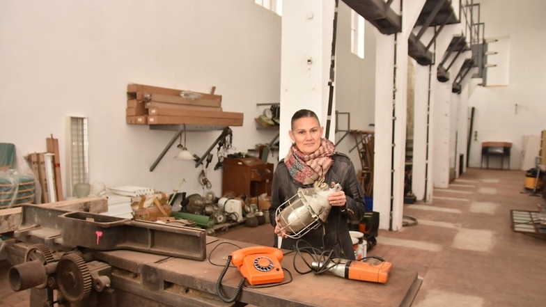 Museumsleiterin Kirstin Zinke zeigt hier stellvertretend eine Industrielampe sowie Telefon und Bohrmaschine aus DDR-Zeiten.