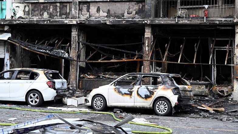 Ausgebrannte Autos stehen vor einem Wohnhaus, in dem am 16. Mai ein Brand wütete. Der mutmaßliche Brandstifer ist unter den Todesopfern.