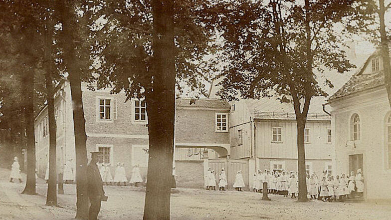 Das Foto vom Kirchgang der Schülerinnen der Mädchenanstalt entstand um 1920. Es zeigt auch das Schwesternhaus mit dem Holzfachwerk.