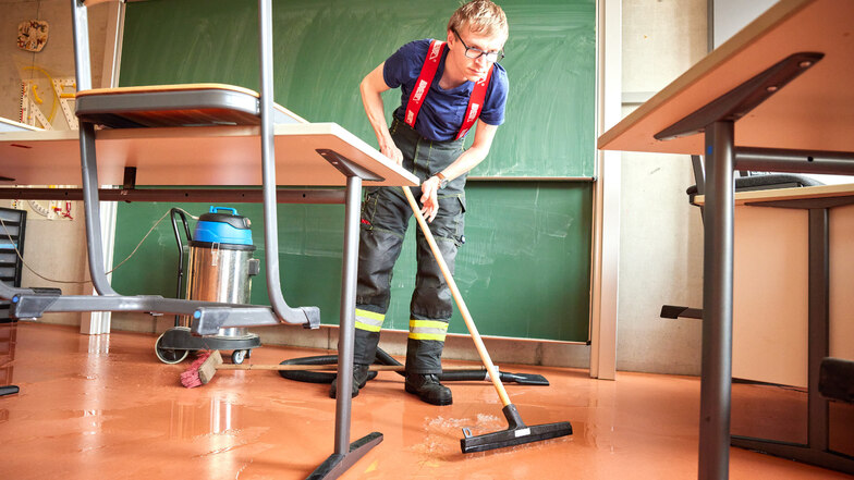 Ein Feuerwehrmann saugt das Wasser in einem Klassenzimmer weg. Betroffen war die Ostseite der Gauß-Oberschule auf dem Pirnaer Sonnenstein.