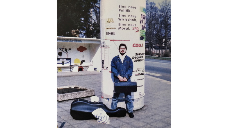 Das Foto zeigt Octavian Ursu 1990 direkt nach der Ankunft in Görlitz vor Litfaßsäule und Bushaltestelle auf der Dr.-Kahlbaum-Allee, in der Nähe des Ständehauses. In dem Koffer in der Hand hält er seine Trompete. Fotos aus der Leipziger Straße hat Ursu nic
