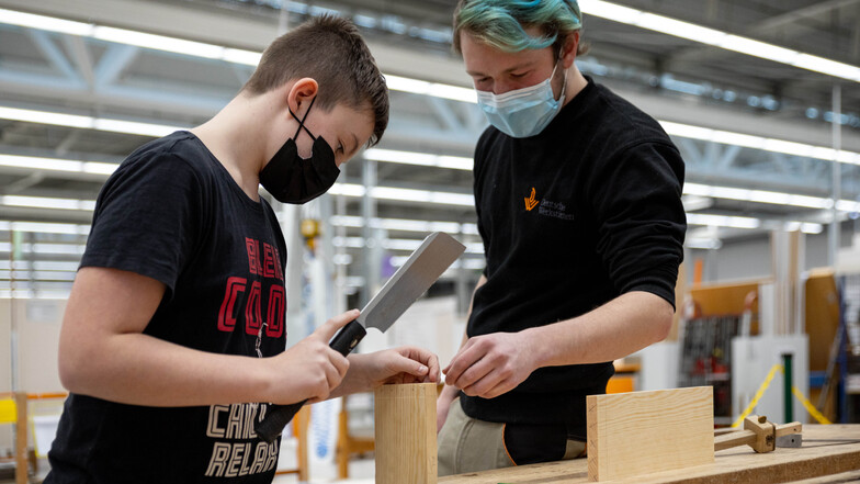 Moritz Eicheler (r.), Azubi in den Deutschen Werkstätten, bringt Nick das Fingerzinken bei, eine spezielle Tischlerverbindung.