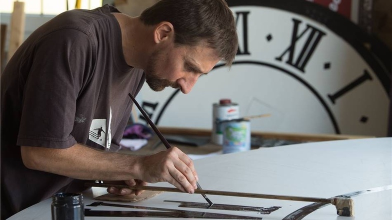 Uhrentechniker Tobias Vogler zeichnet die römischen Ziffern auf ein neues Zifferblatt für die Lukaskirche.
