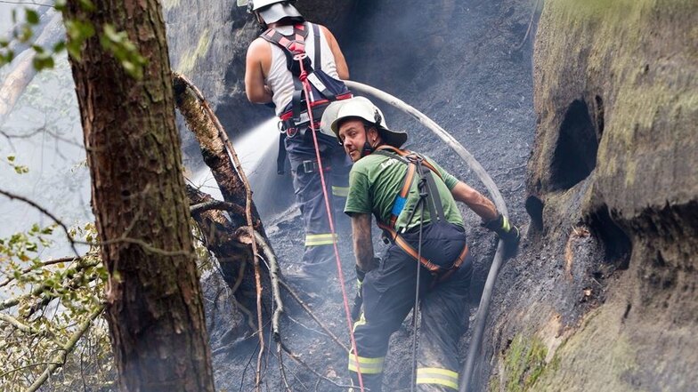 Von der Bergwacht mit Seilen gesichert kämpfen sich die Kameraden der Feuerwehr zum Brandherd vor. Darüber, wo genau das Feuer aber entstanden ist, konnte gestern Kreisbrandmeister Karsten Neumann noch keine Auskunft geben.