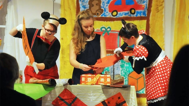 Alice packt zusammen mit ihren Freunden Mickey und Minnie in der Geschenkewerkstatt kleine Päckchen für die Kinder.
