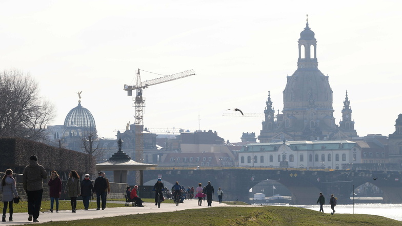 Passanten gehen am Ufer Elbe vor der Kulisse der Dresdner Altstadt mit der Frauenkirche entlang.