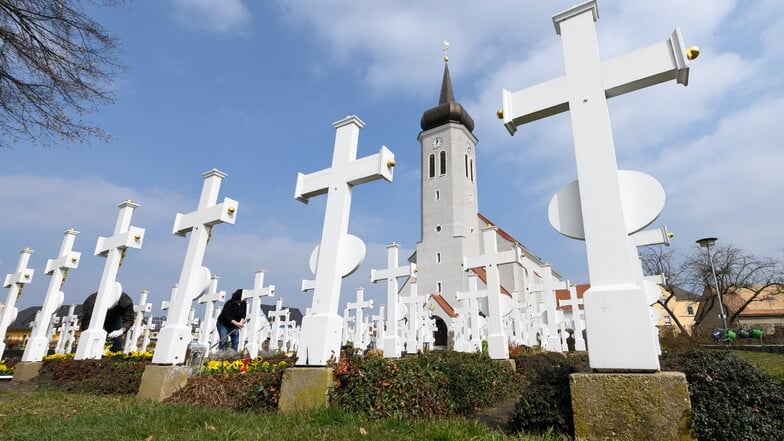 Grabkreuze stehen auf einem Friedhof vor der Kirche der Gemeinde "Sankt Katharina" in Ralbitz.