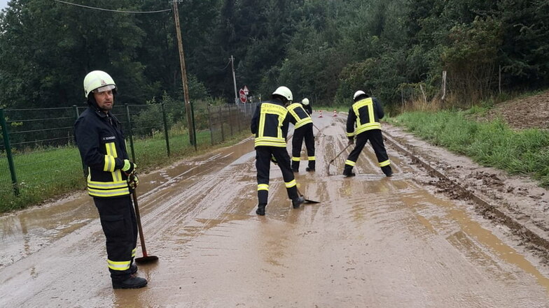 In Handarbeit begannen die Seifersdorfer Feuerwehrleute damit, den Schlamm von der Straße zu kehren.