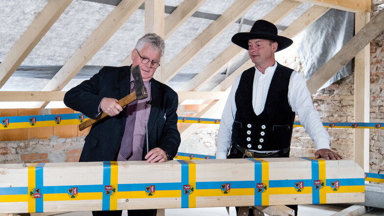 Landrat Bernd Lange (links) schlägt beim Richtfest des neuen Landratsamtes in Görlitz einen Nagel in einen Balken. Rechts: Maik Seeliger von Holzbau Seeliger.