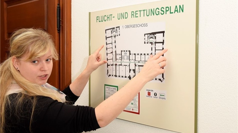 Stadtsprecherin Diana Schulze zeigt einen der Fluchtpläne, die an mehreren Stellen im Rathaus hängen.