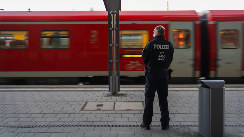 Ein Polizeibeamter blickt am Hofer Bahnhof auf die Insassen eines einfahrenden Zuges.