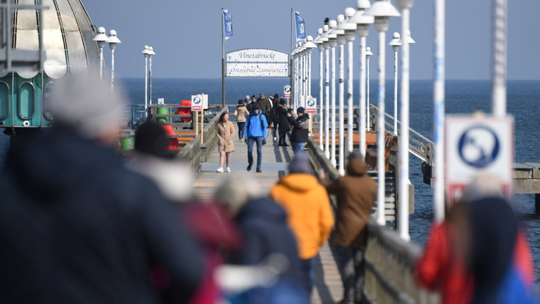 Menschen gehen auf der Seebrücke von Zinnowitz auf der Insel Usedom spazieren.