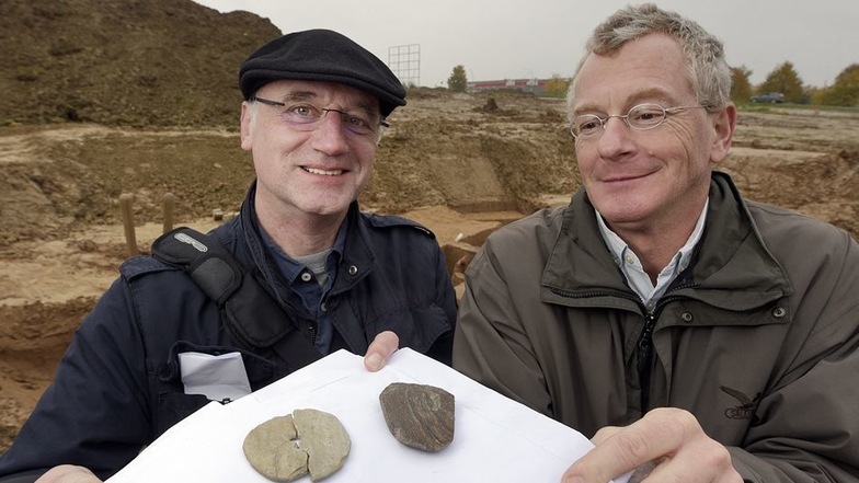 Dr. Christoph Heiermann (links) und Dr. Michael Strobel zeigen eine Schmuckscheibe aus Schiefer und ein Steinbeil.