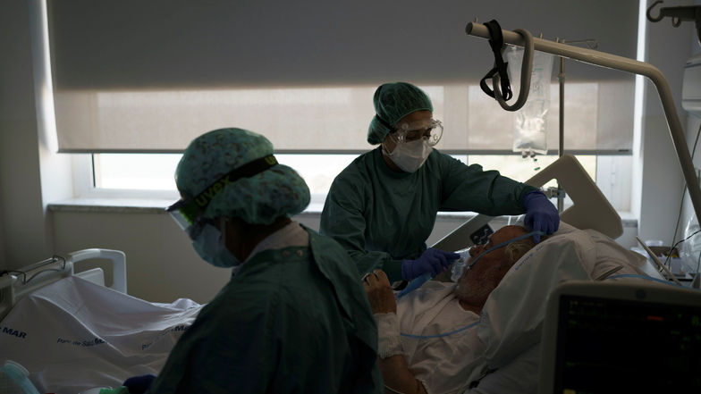 Medizinische Mitarbeiterinnen in Schutzausrüstung behandeln einen Corona-Patienten in einem Krankenhaus.
