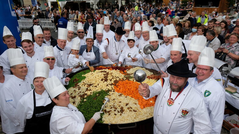 Köche des Internationalen Kochkunstvereins zu Leipzig stehen auf dem Marktplatz um eine Pfanne herum. Die Köchinnen und Köche versuchten, die größte Portion des Traditionsgerichtes ·Leipziger Allerlei· zuzubereiten.