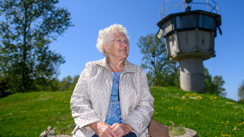 Die Zeitzeugin Gitta Kappe sitzt am "Grenzdenkmal Hötensleben" vor einem ehemaligen Wachturm.
