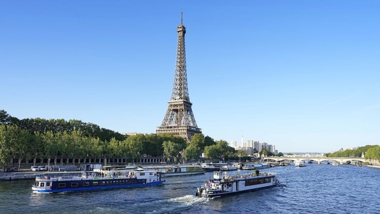 Ein Boot und ein Lastkahn fahren vor dem Eiffelturm auf der Seine: Kurz vor Beginn der Olympischen Spiele werden die Eintrittspreise für den Turm kräftig erhöht.