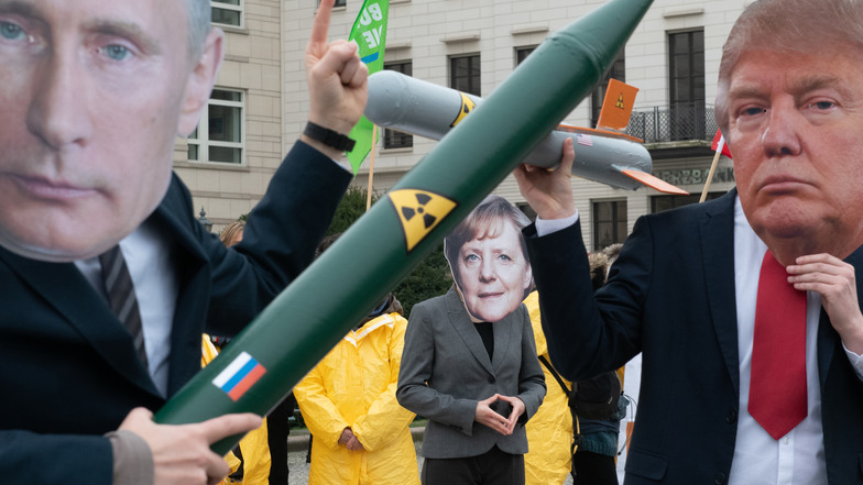 Demonstranten mit einer Putin und Trump-Maske und einer Merkel-Maske stehen sich mit Raketen-Modellen auf dem Pariser Platz in Berlin gegenüber. Sie protestierten mit der Aktion gegen das Aus des INF-Abrüstungsabkommen zwischen Russland und den USA.