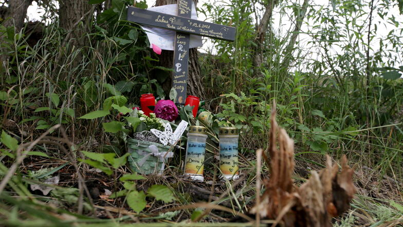 Am Kiessee in Dresden-Zschieren haben Freunde des ertrunkenen jungen Mannes ein Holzkreuz, Blumen und Kerzen aufgestellt.