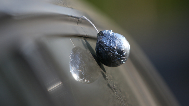 Ein so genannter Querdenker-Bommel hängt an einem Auto in Pirna. Das gebastelte Stück besteht vorwiegend aus Aluminiumfolie und einem längeren Faden. Es soll die Verbundenheit zur Querdenker-Bewegung symbolisieren.