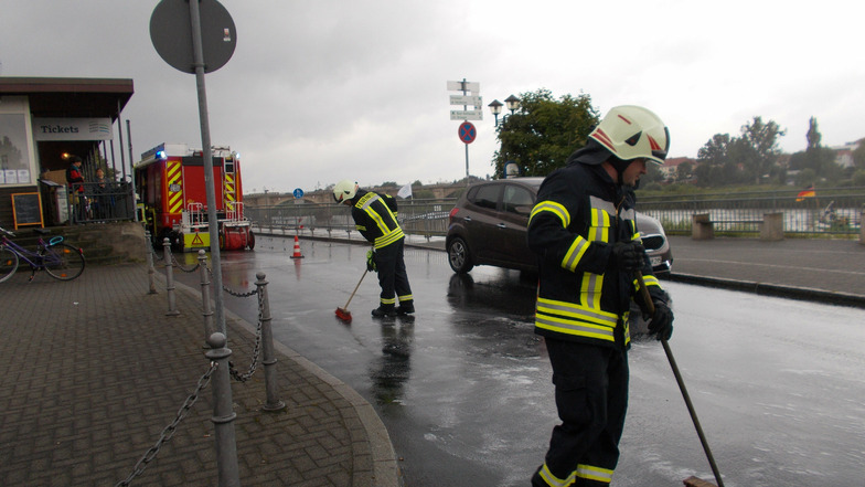 Mitglieder der Feuerwehr Pirna beseitigen eine Ölspur auf der Brückenstraße.