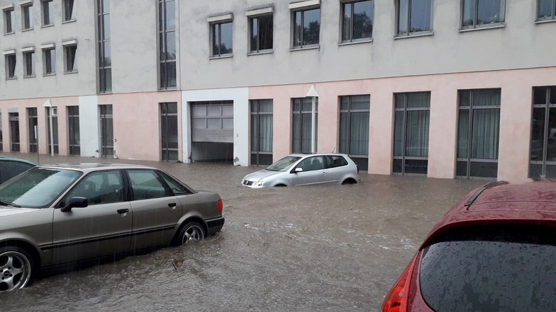 Nach einem Unwetter mit Starkregen stehen Autos auf einem Parkplatz im Wasser.