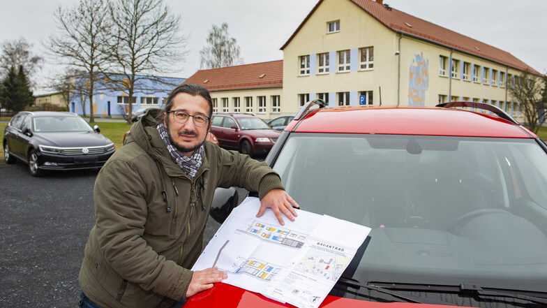 Thiendorfs Bürgermeister Dirk Mocker zeigt an der Grundschule Ponickau den Plan fürs künftige Hortgebäude.