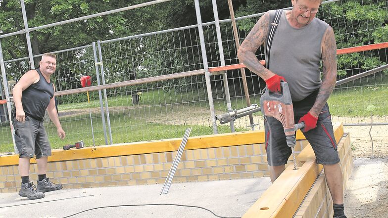 Jens Pannasch (li.) und Heinz Steinke von der Holzbaufirma Rösch bringen die Fußschwellen an, auf die Fachwerkwand und Dachkonstruktion gesetzt werden.