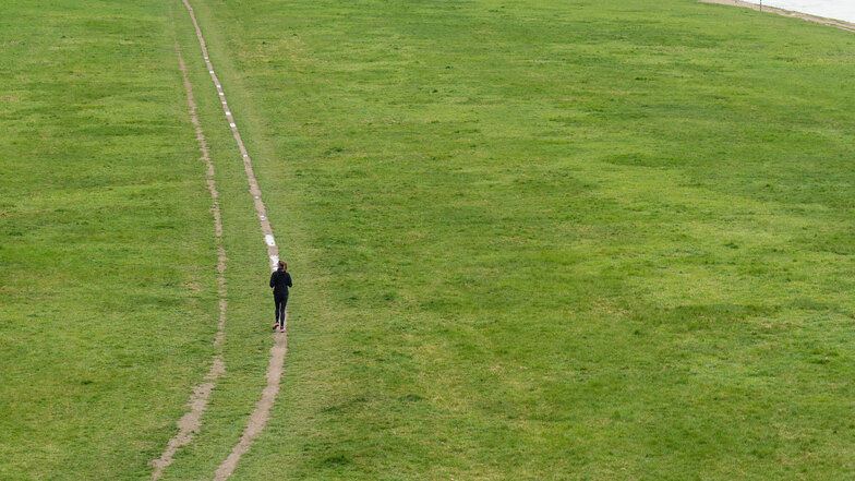 Allein auf weiter Flur: Eine Joggerin läuft im April 2020 auf den Elbwiesen in Dresden. Foto: Jürgen Lösel