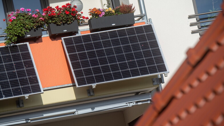 Solarmodule für ein sogenanntes Balkonkraftwerk hängen an einem Balkon. In Sachsen werden solche Anlagen bald gefördert.